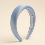 A light blue satin headband with a visible brand label on the inside, displayed against a neutral background.