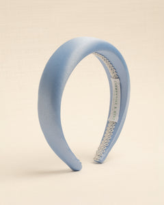 A light blue satin headband with a visible brand label on the inside, displayed against a neutral background.