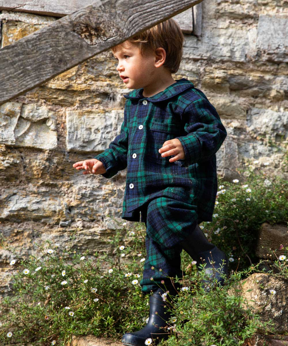 Child in a black watch tartan winter pyjamas standing outside