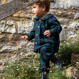 Child in a black watch tartan winter pyjamas standing outside