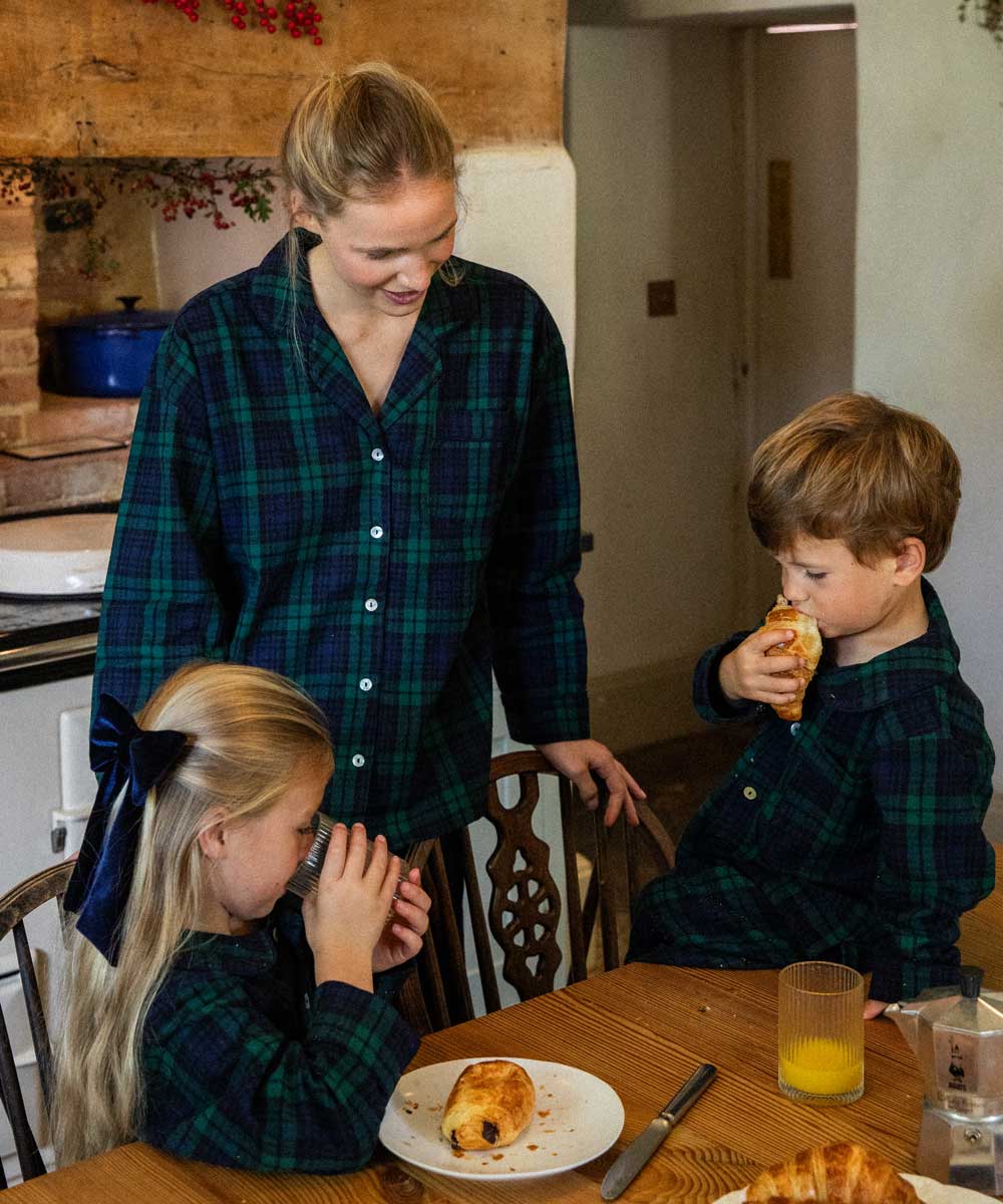 Woman and two children in a kitchen setting wearing black watch tartan cotton pyjamas