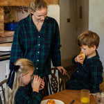 Woman and two children in a kitchen setting wearing black watch tartan cotton pyjamas