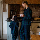 Woman and child in matching black watch tartan plaid pyjamas standing in a kitchen.