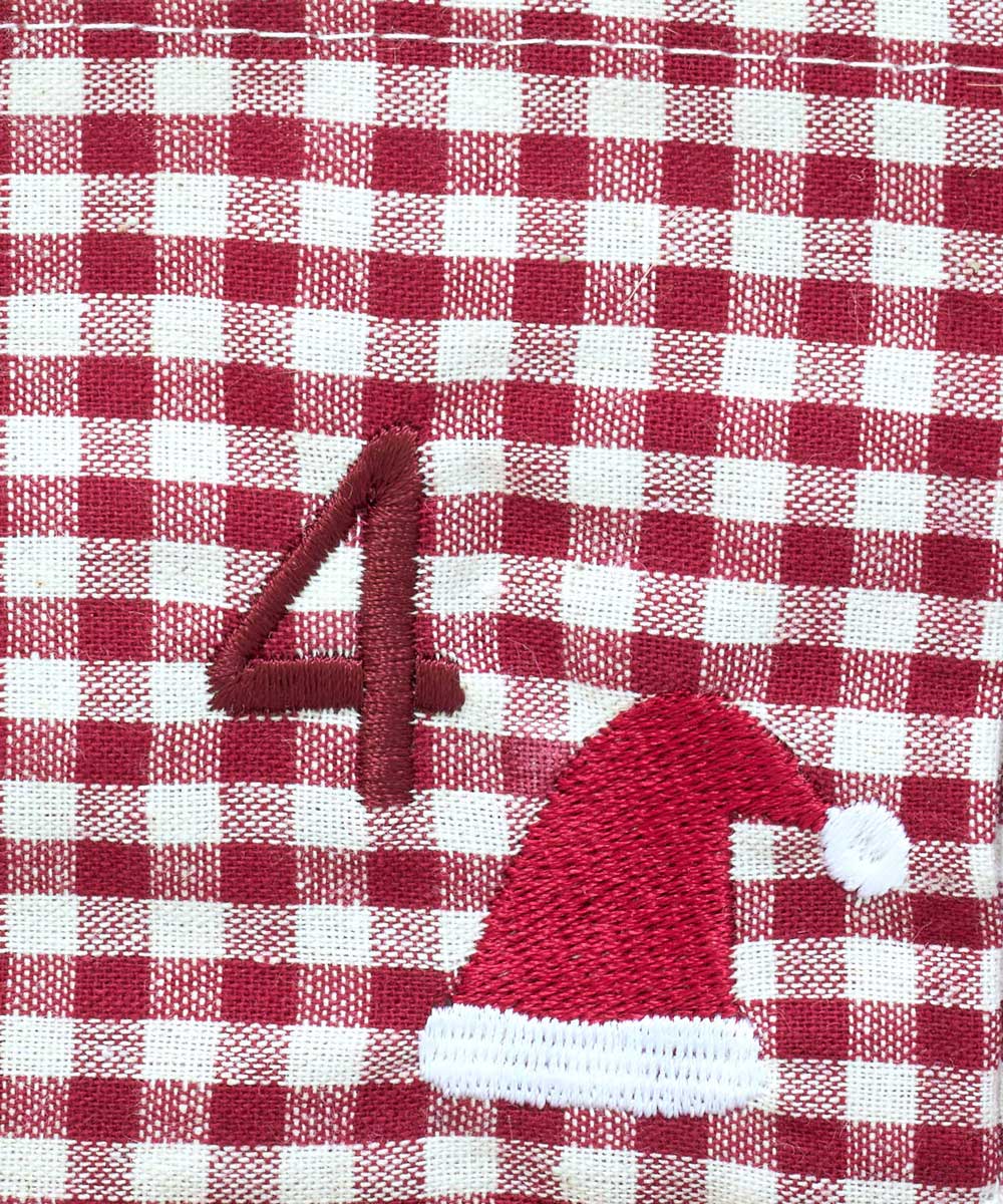 A close-up of a red and white gingham fabric surface with an embroidered red number 4 and a red Santa hat with a white pom-pom.