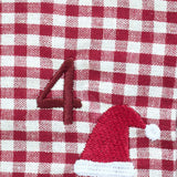 A close-up of a red and white gingham fabric surface with an embroidered red number 4 and a red Santa hat with a white pom-pom.