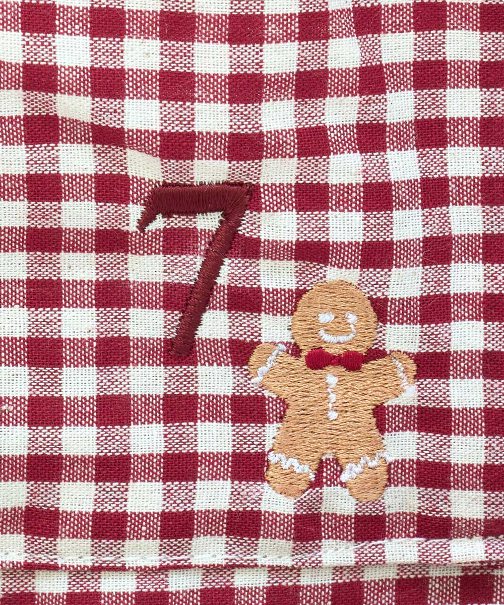 Close-up of a red and white gingham checkered fabric with an embroidered brown number 7 and a small gingerbread man motif.