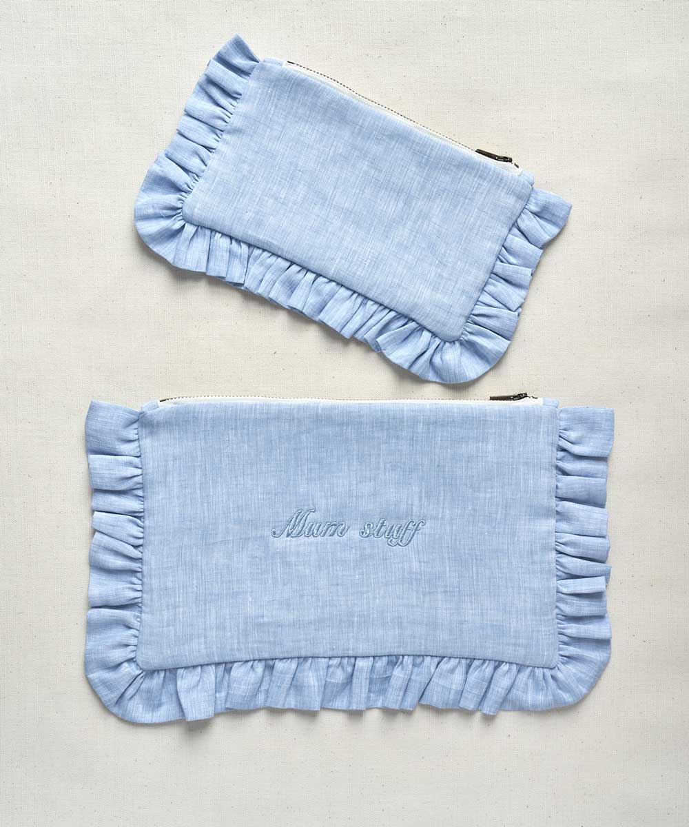 Two light blue pouches with ruffled edges on a beige background