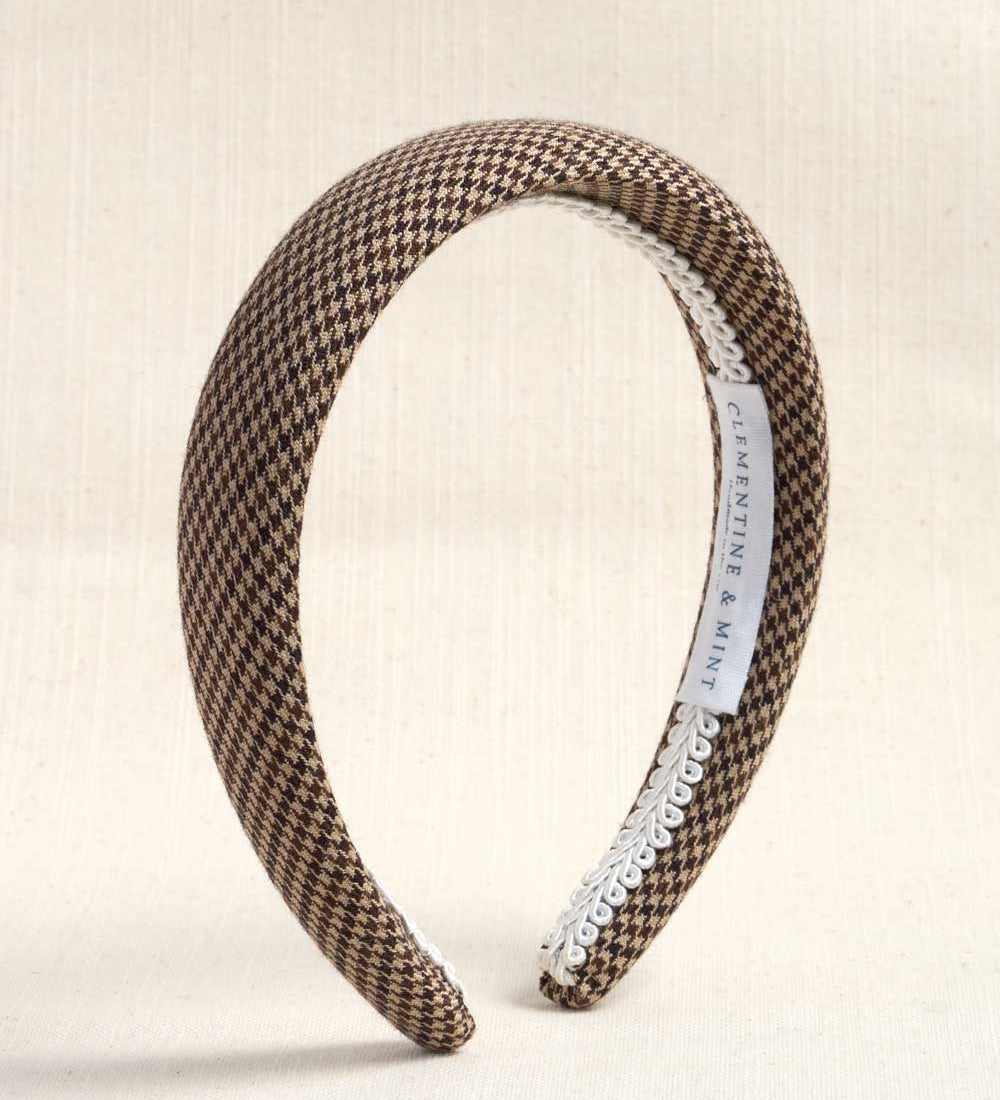 A wide headband with a brown and beige houndstooth pattern, finished with a white trim on one side and a white interior label reading 'CLEMENTINE & MINE'.