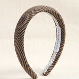 A wide headband with a brown and beige houndstooth pattern, finished with a white trim on one side and a white interior label reading 'CLEMENTINE & MINE'.