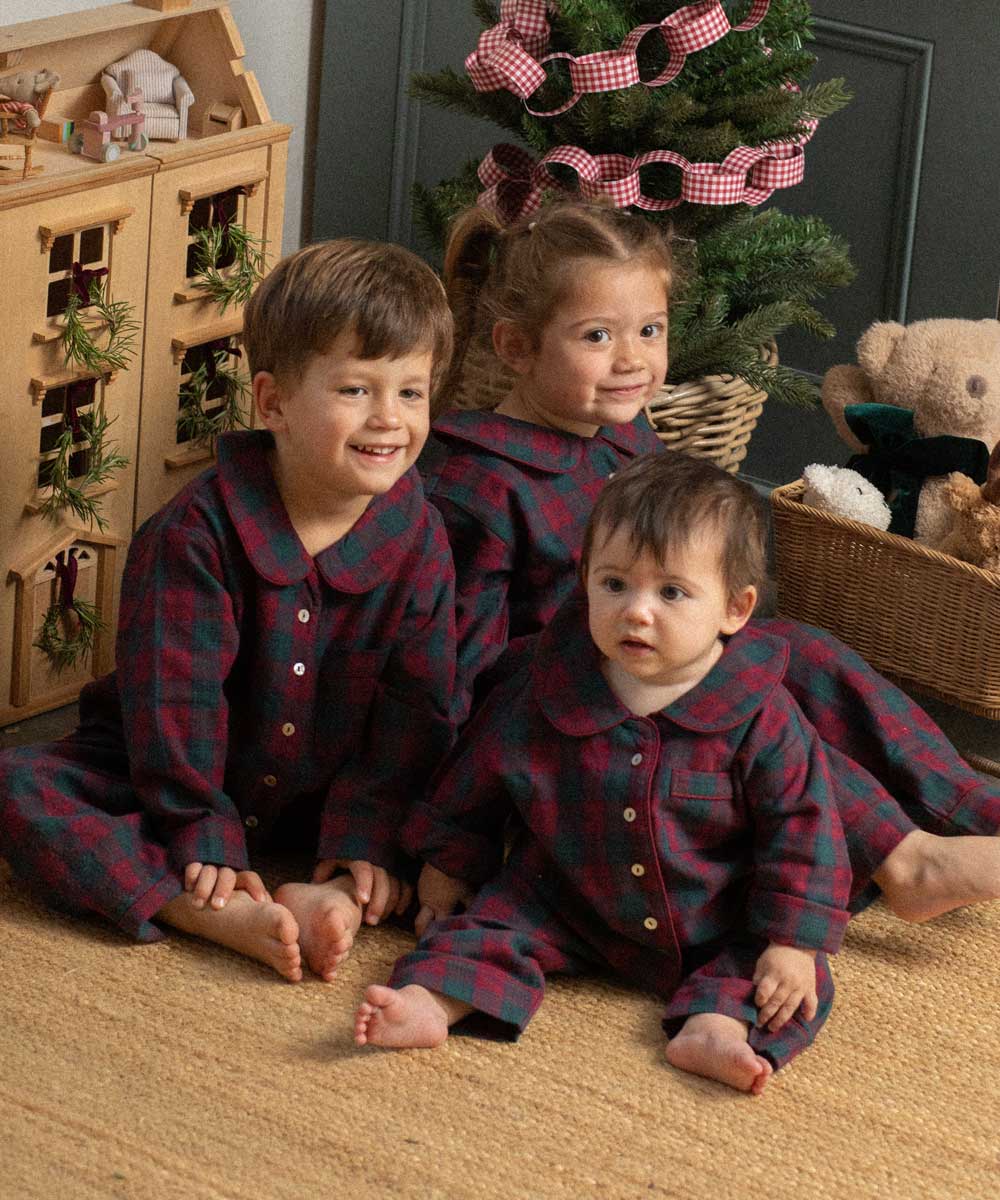 three children wearing burgundy tartan pyjamas