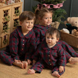 three children wearing burgundy tartan pyjamas