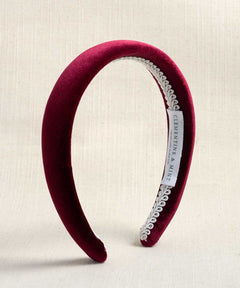 A deep burgundy velvet headband with a silver beaded trim, shown on a neutral textured beige background. A white paper tag is attached to the headband displaying the brand 'CLEMENTINE & MINT'.