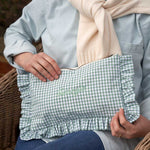 Person holding a green and white checkered ruffled pouch with 'Georgie' embroidery.