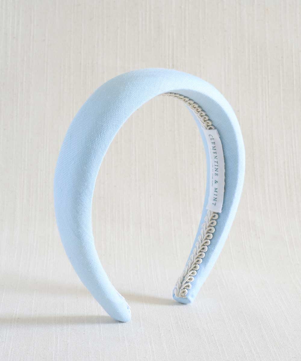 Light blue headband with a braid detail on a beige background