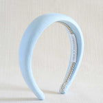 Light blue headband with a braid detail on a beige background
