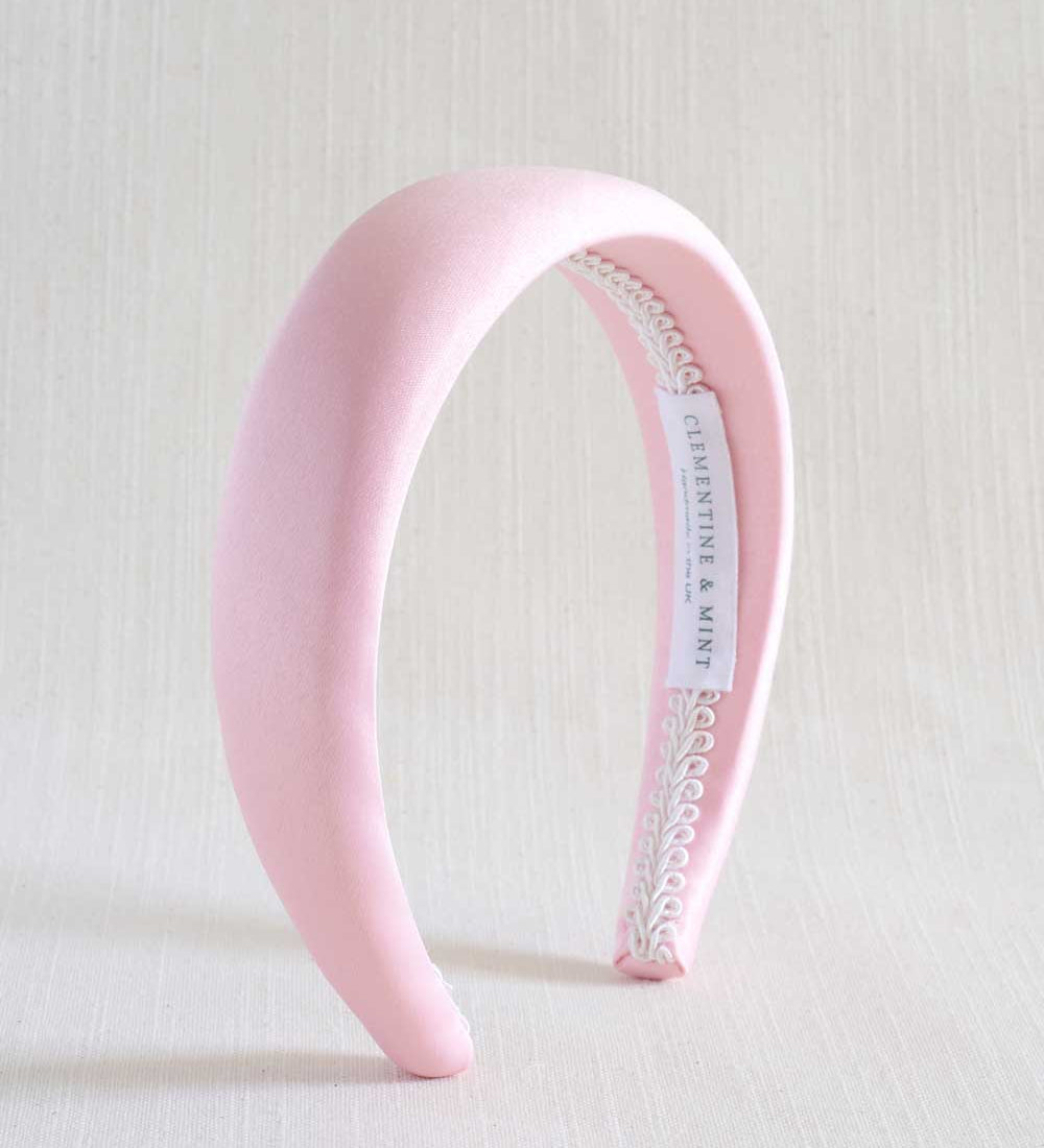 Light pink satin headband with a white label on a light background