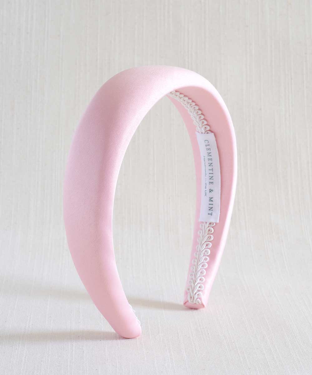 Light pink satin headband with a white label on a light background