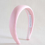 Light pink satin headband with a white label on a light background