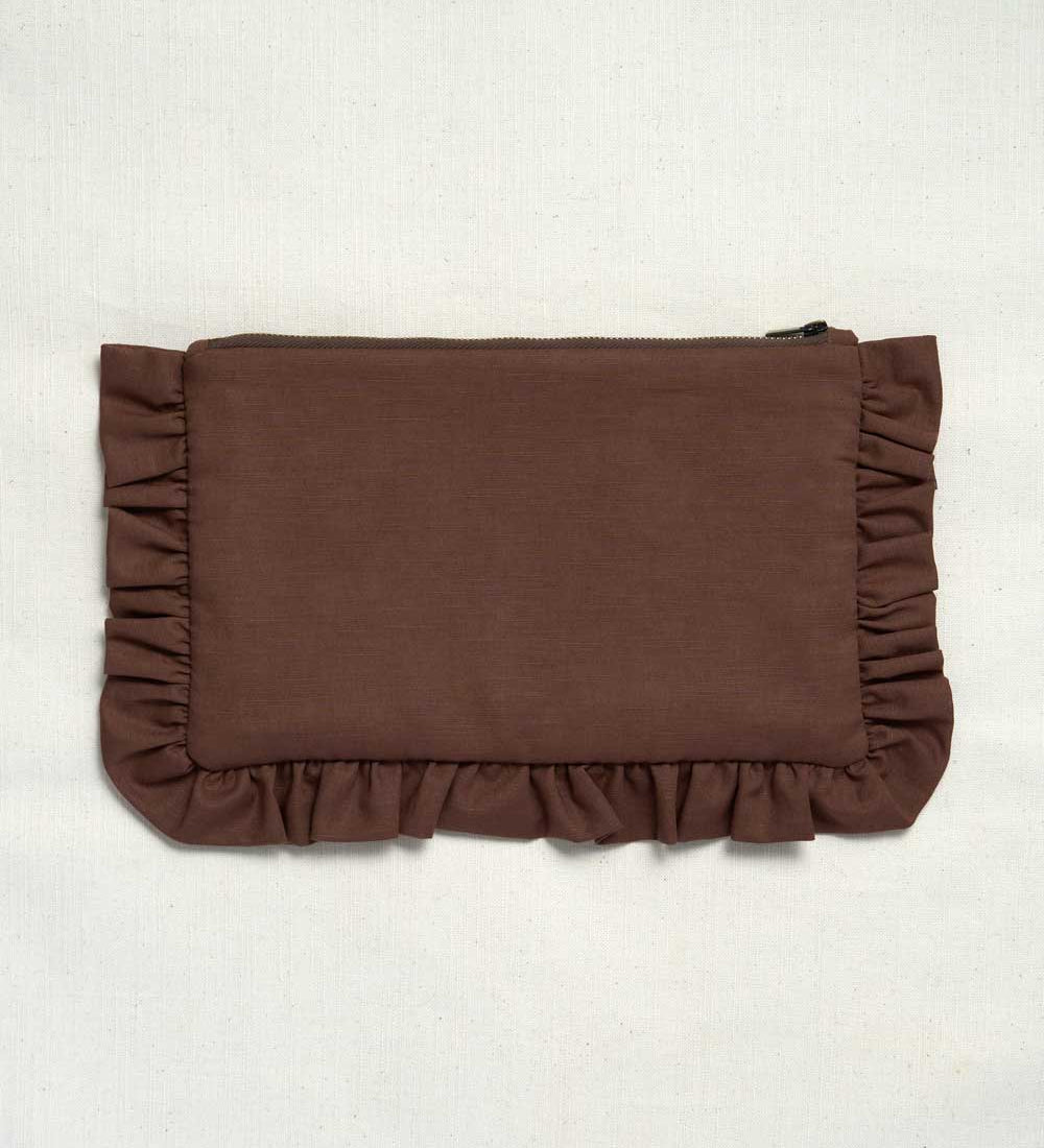 A brown fabric clutch or pouch with ruffled trim on all sides, photographed flat against a light off-white textured background.