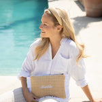 Woman in a white shirt holding a pouch wearing a straw headband 