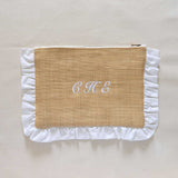 Raffia textured pouch with white ruffled edges and initials 'C H E' on a beige background